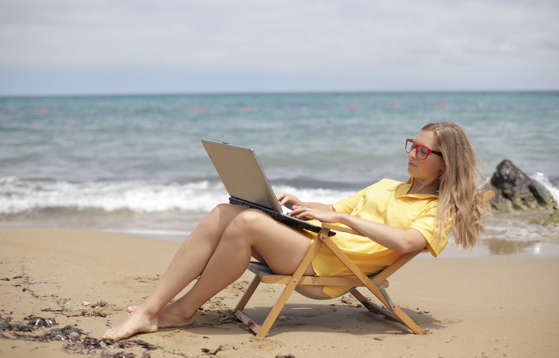 woman in yellow shirt sitting on brown wooden folding chair on beach